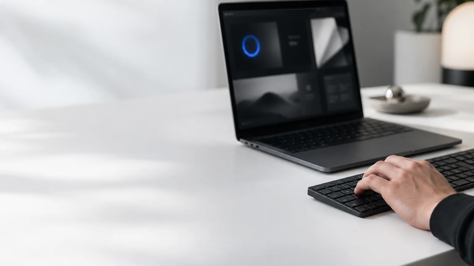 Main sur un clavier noir devant un ordinateur affichant une interface contrastée avec un anneau de focus bleu