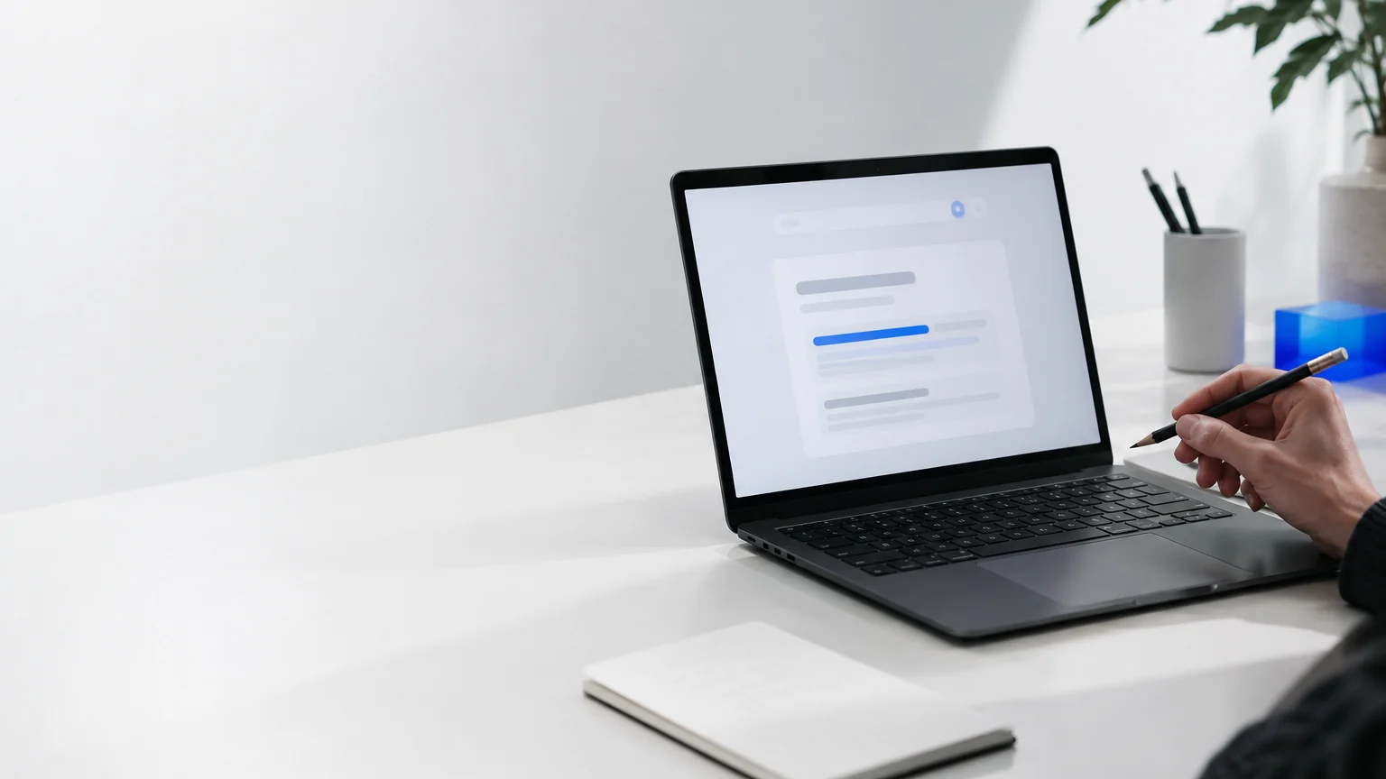 Ordinateur portable affichant un résultat de recherche flou avec une barre bleue, et un crayon
