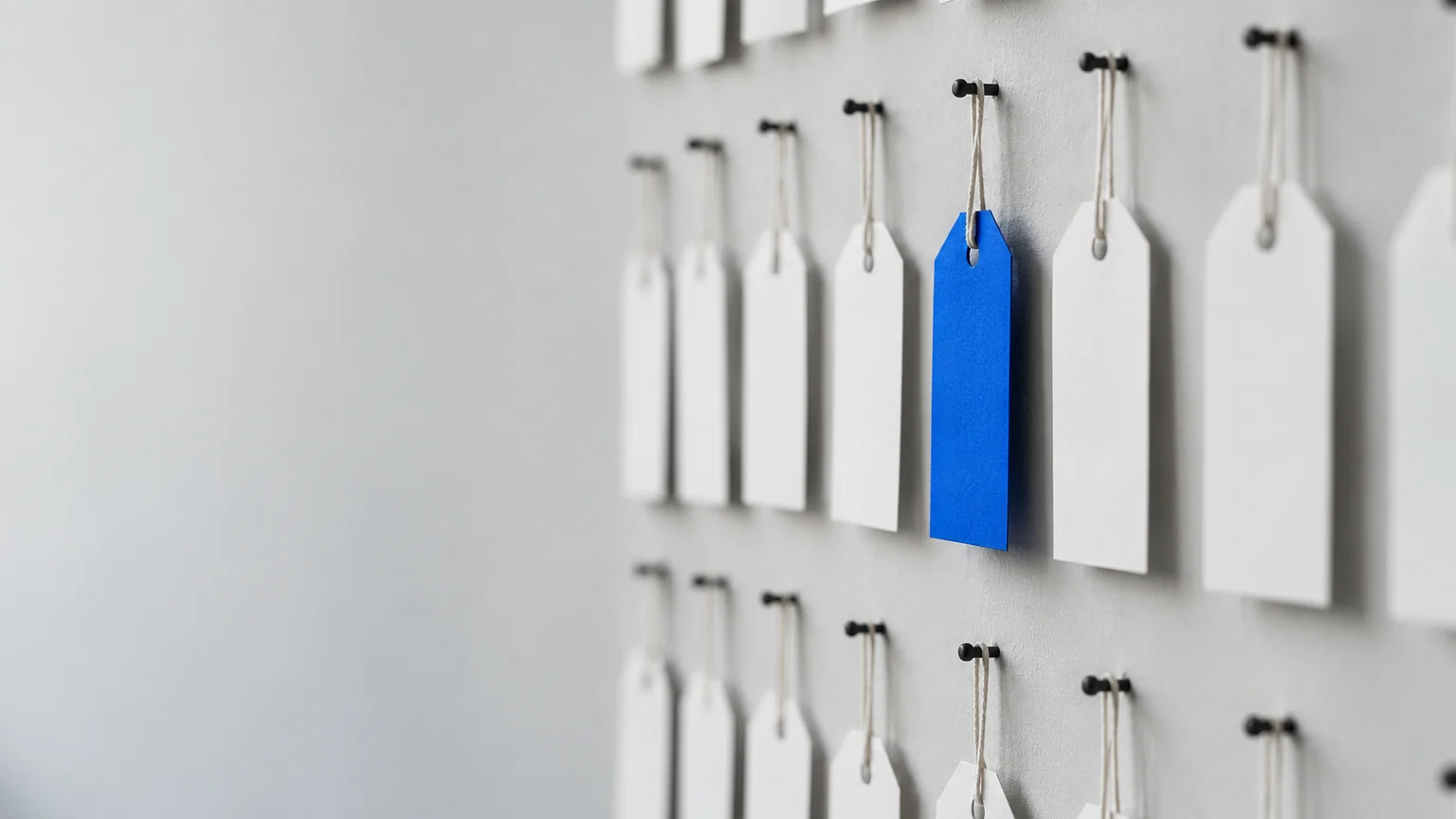 Rangées d'étiquettes blanches sur un mur gris clair dont une étiquette bleue