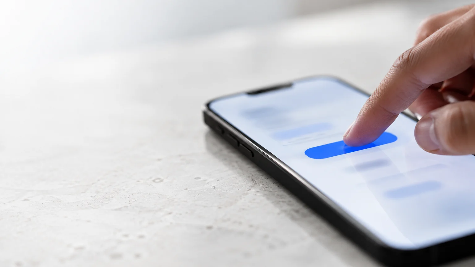 Doigt touchant un smartphone affichant une interface épurée floue avec un bouton bleu