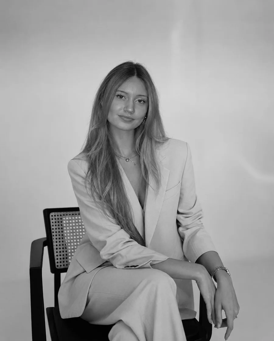 Studio portrait in a light suit, seated on a cane chair